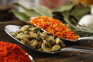 Spoon with spices on dark wooden table close up