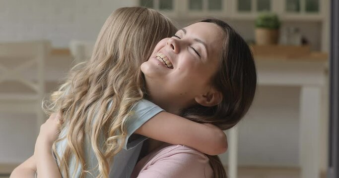 Happy affectionate family single mum and cute little child daughter embracing bonding laughing together, young mother foster parent hugging small kid girl cuddling enjoy tender moment of love at home