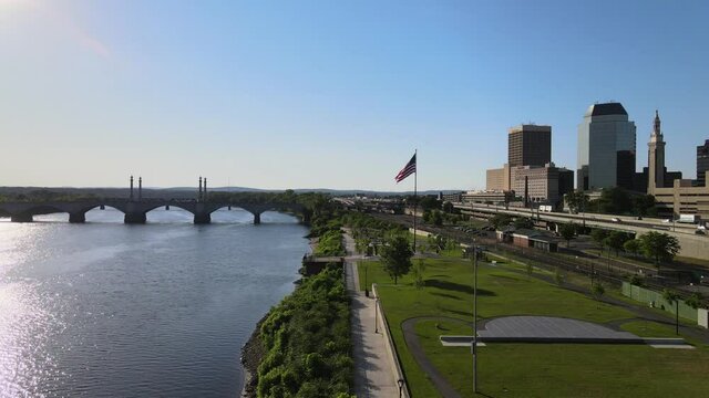 Aerial 4K video of large American flag flying in park along Connecticut River in Springfield, MA