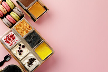 Mousse desserts in square plastic boxes with different toppings on pink table