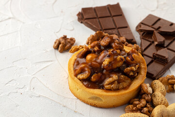 Tart with nuts and chocolate on white textured background