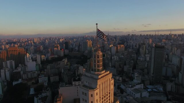 Sao Paulo flag atop Altino Arantes Building at sunset, aerial