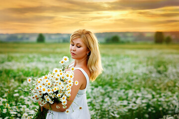 Naklejka na ściany i meble beautiful blonde girl laughing in a field of daisies at sunset with a bouquet of camomiles