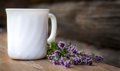 a white Cup of tea and a bunch of spicy herb thyme on a rustic background