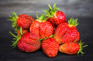 red ripe strawberries close up on a black wooden background