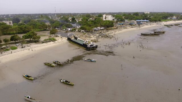 An aerial Flyby shot of Crowd of African people on a Low Tide at the Beach of Bagamoyo, Tanzania