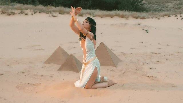 woman Queen Nefertiti. scenery Egyptian pyramids, green oasis desert. White sexy vintage dress. Gold bracelets belt traditional jewelry. goddess Cleopatra dances, plays strew yellow sand touches hands