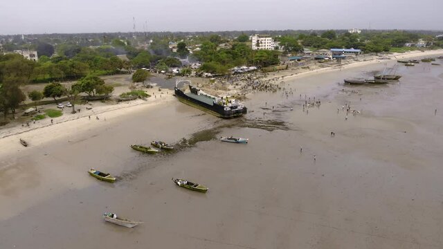 An aerial Flyby shot of Crowd of African people on a Low Tide at the Beach of Bagamoyo, Tanzania