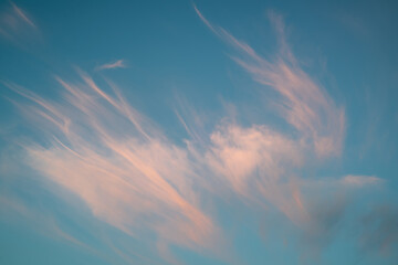 Blue-turquoise sky at sunset with pink calm clouds. Beautiful sky background.