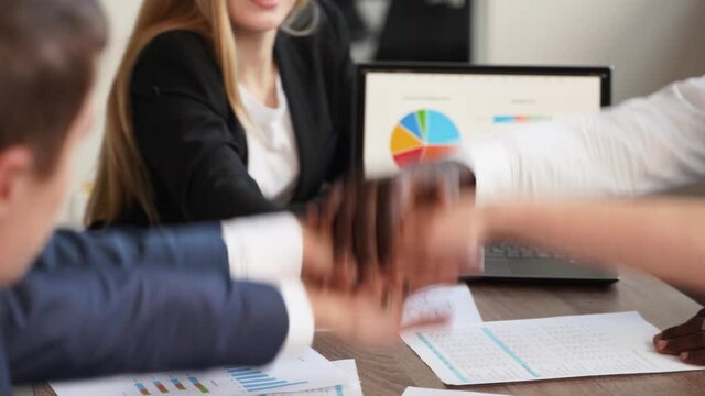 International business team showing unity with their hands stacked together in pile. Black african-american hand on top. Mixed race multiethnic group join their hands. Businessman and businesswoman.
