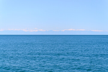 Obraz premium blue sea and mountains with clouds on the horizon