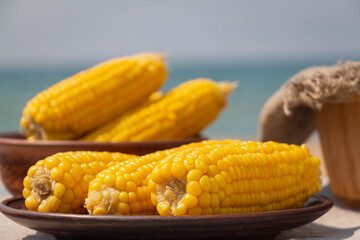 Boiled corn on an earthenware plate, closeup, selective focus. Rustic still life.