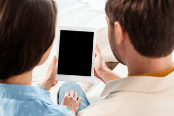 Back view of young couple holding digital tablet with blank screen