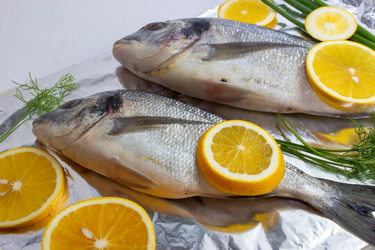Two fresh dorada fish with lemon and dill on top