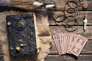 Tarot cards deck and book of magic on the old wooden table background.