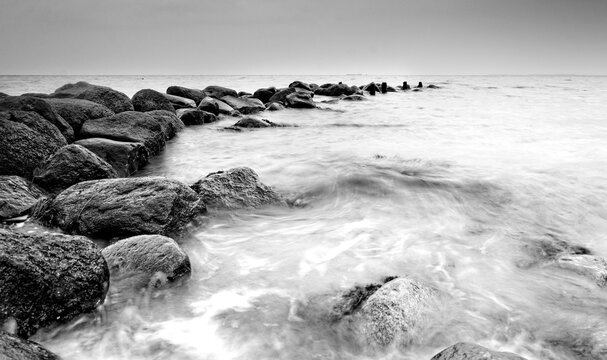 Breakwater Stones in the ocean dark mood for postcards about grief mourning or peaceful and soothing meditation and relaxation