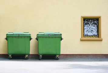 Garbage cans on the street near the wall of building