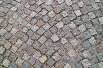 Old stone block road pavement with moss. Texture and background concept.