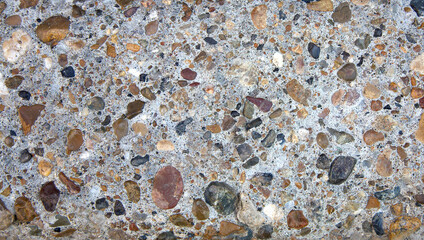 Fragment of the texture of the border with multi-colored pebbles in cement as a background
