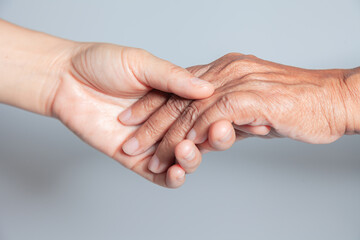 Old and young holding hands on white background . Close-up of tender Young woman holding hands with a senior lady hands show encourage