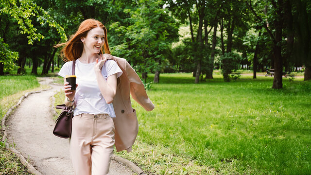 Bleisure Travel, bizcation concept, new trend in travel industry. Red-haired business woman enjoys vacation in park on nature background. Corporate traveller wants to enjoy leisure time during trip