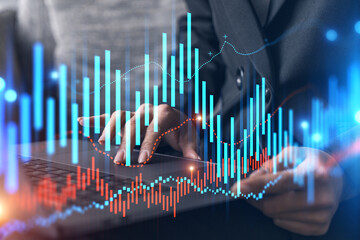 Businesswoman typing on computer in office. Fiancial graph hologram. Double exposure.