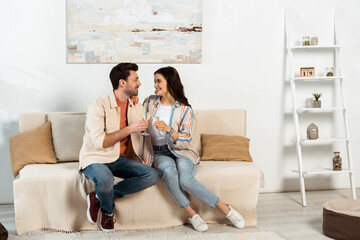 Young couple smiling at each other while drinking champagne at home