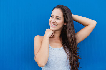 Obraz na płótnie Canvas Face portrait of a beautiful young woman smiling with blue background