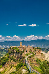 Fototapeta na wymiar View of the medieval town of Civita di Bagnoregio, located on the top of a spur of tuff rock, in the middle of the valley of the badlands. Connected to the city by a small bridge, mule track.