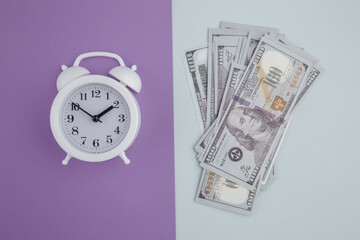 Alarm clock and dollars on colorful background. Time is money concept.