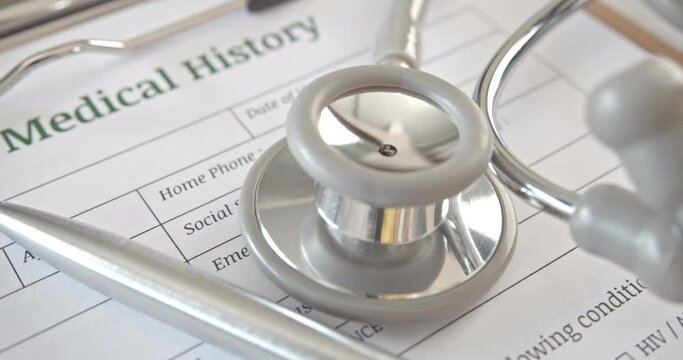 Patient medical history form on a table in a doctor or physician office. Stethoscope and pen on a paper used to record symptom and medicine that practitioner dispense or give to sick person in hospita