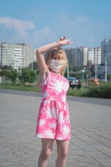 Happy little girl of five in a protective mask has fun on a city street after isolation