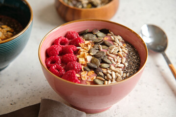 Healthy food - smoothie bowl topped with raspberries, granola, seeds and chia. Closeup view