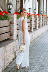 A girl in a light summer suit with a bag. Demonstration of clothing