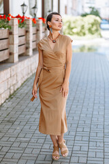 A girl in a light beige dress. Demonstration of clothing