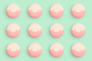 Macaroons pattern on colored background, twelve colorful french cookies macarons. Beige, pink french cookies macarons on green background. Gift for congratulations.