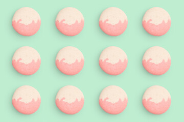 Macaroons pattern on colored background, twelve colorful french cookies macarons. Beige, pink french cookies macarons on green background. Gift for congratulations.