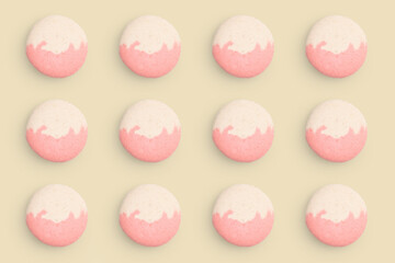 Macaroons pattern on colored background, twelve colorful french cookies macarons. Beige, pink french cookies macarons on yellow background. Gift for congratulations.