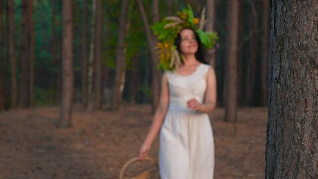 Woman in White Dress with Wreath and Basket Walks In Pine Forest. Slow motion 60 FPS