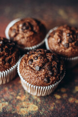 Beautiful chocolate muffins with pieces of chocolate on dark background