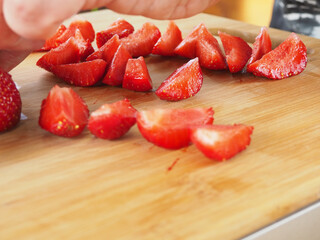 cook cuts strawberries on a wooden Board. poster. in the summer