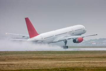 White passenger aircraft moves at the runway in heavy rain. Take-off with strong spray