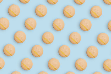 Macaroons pattern on colored background, a pattern of colorful french cookies macarons. Beige french cookies macarons on mint blue background. Gift for congratulations.