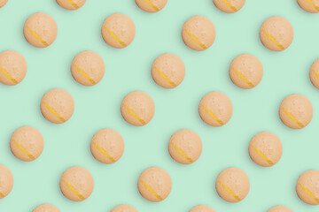 Macaroons pattern on colored background, a pattern of colorful french cookies macarons. Beige french cookies macarons on green background. Gift for congratulations.