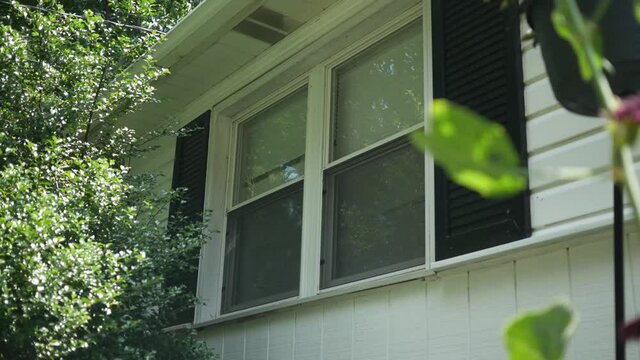 A pair of bedroom windows on residential ranch home with downed blinds on sunny afternoon