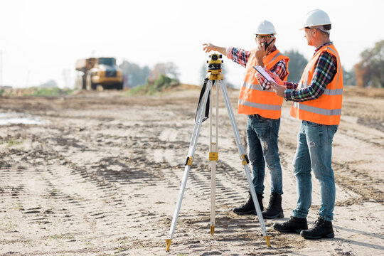 Two road construction workers using measuring device on the field