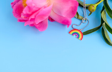 rainbow pendant as an LGBT symbol and pink peony flower on a blue background