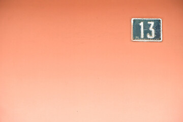 Number 13, thirteen, offset in corner on graded pink background.