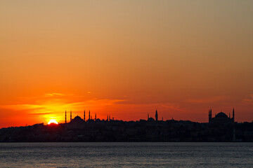 Naklejka premium Silhouette of Istanbul with the domes and minarets of Blue Mosque and Hagia Sophia, at the sunset, from Bosphorus, Turkey