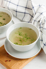Homemade bone broth in a white bowl on a wooden background. The concept of healthy eating. Copy space.